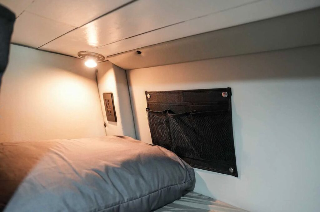 Van bunk bed interior with reading light and organizer.