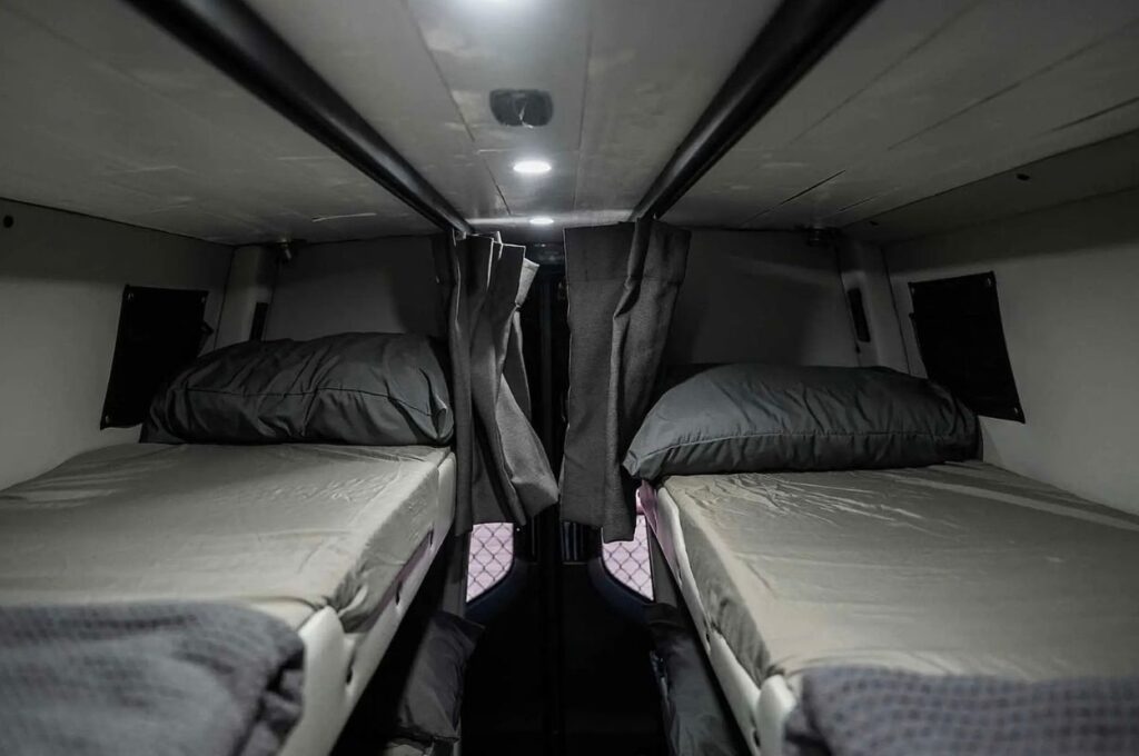 Custom van interior featuring dual bunk beds with curtains.
