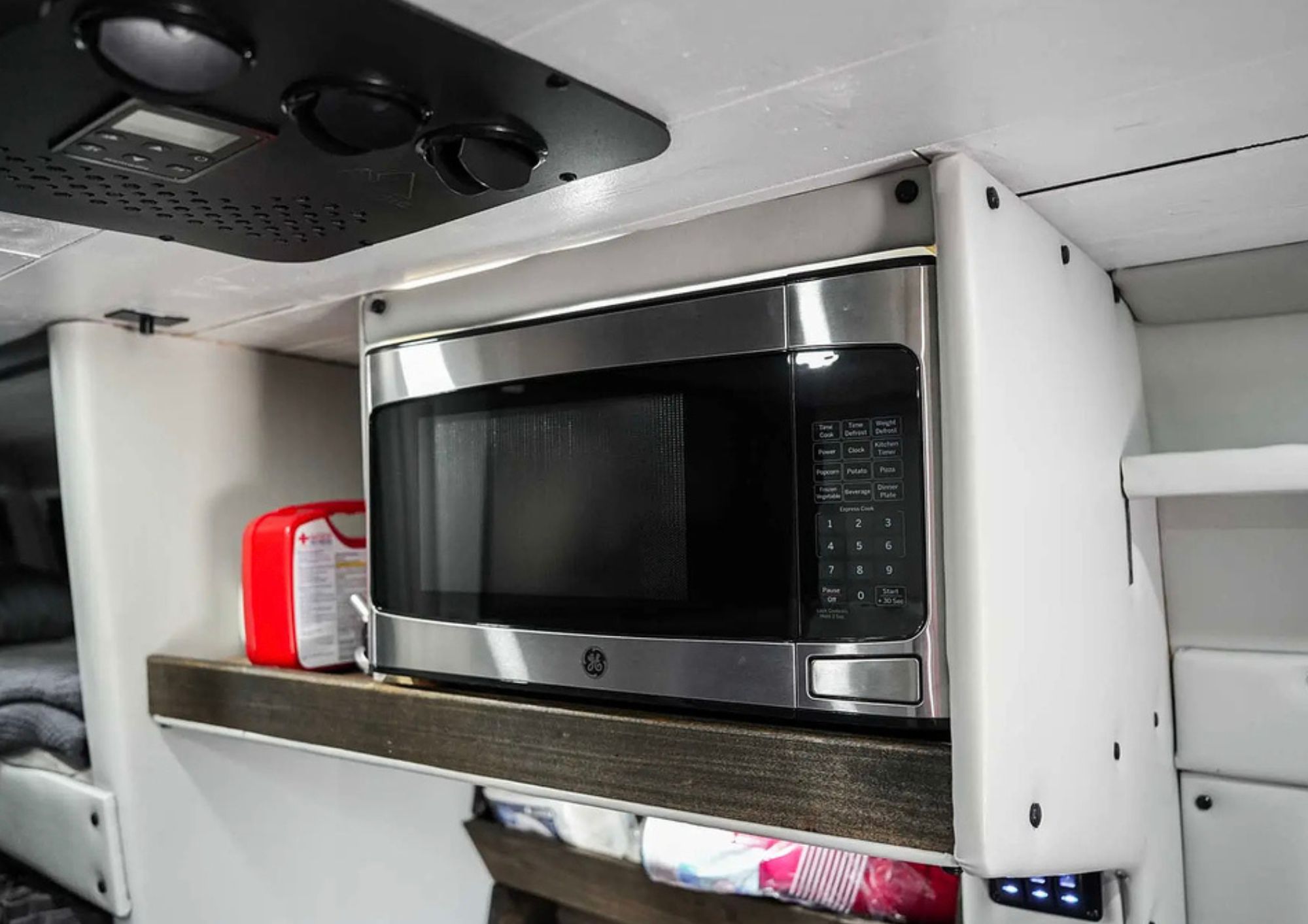 Stainless steel microwave mounted inside custom camper van.